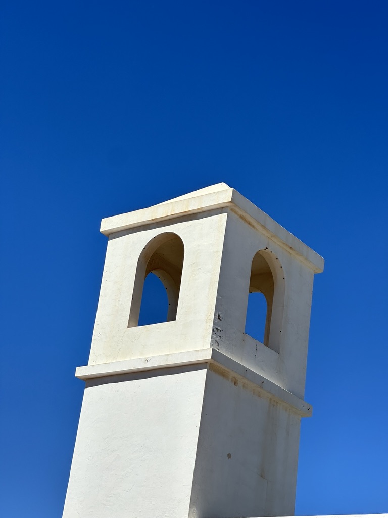 Whitewashed chimney tower against a deep blue sky