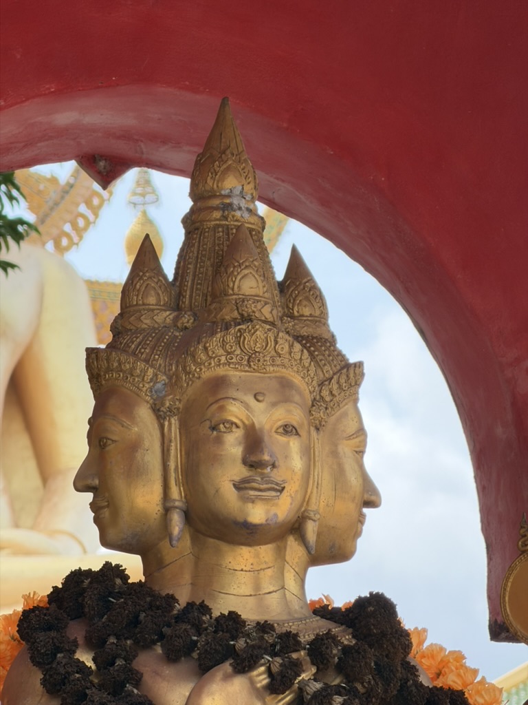 Four-faced Brahma shrine beneath a red temple arch